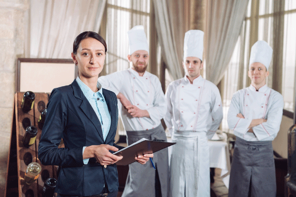 Mujer con saco azul junto a tres hombres con vestimenta de chef