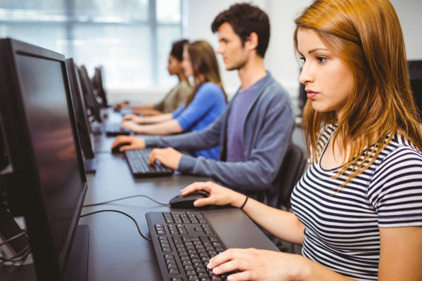 Hombres y mujeres sentados frente a una computadora
