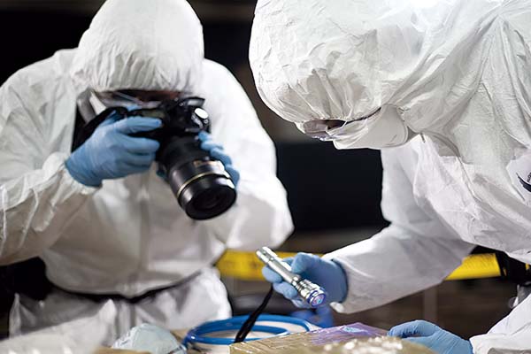 Personas con vestimenta blanca, cubrebocas y guantes azules con cámara y una lámpara