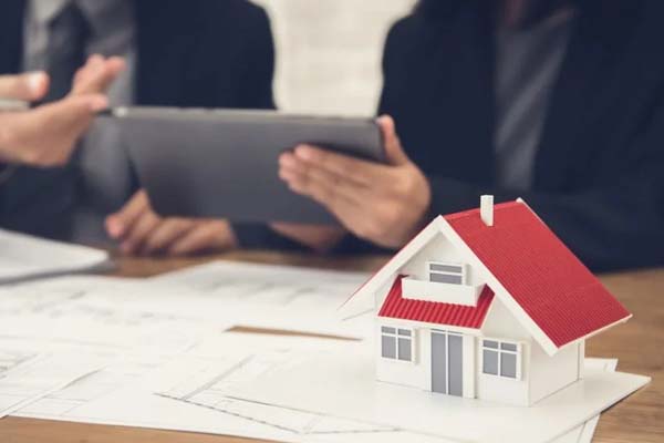 Hojas blancas sobre una mesa y la figura de una casa