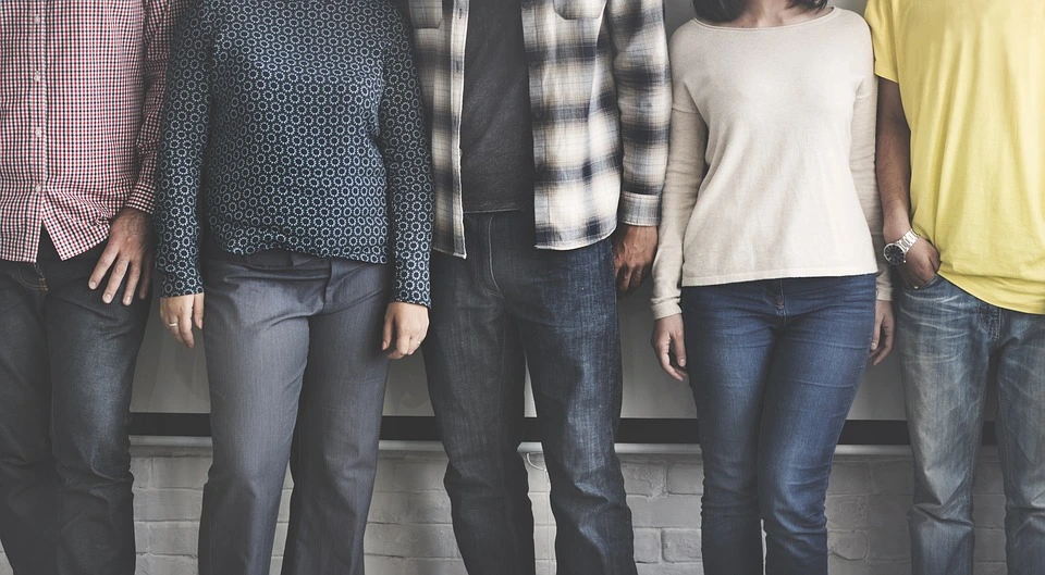 Cuerpo de hombres y mujeres con pantalon de mezclilla azul y diferentes playeras de una Educación Profesional