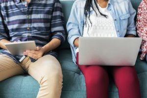 Mujer sentada con una laptop en las piernas y hombre sentado con una tablet en las manos