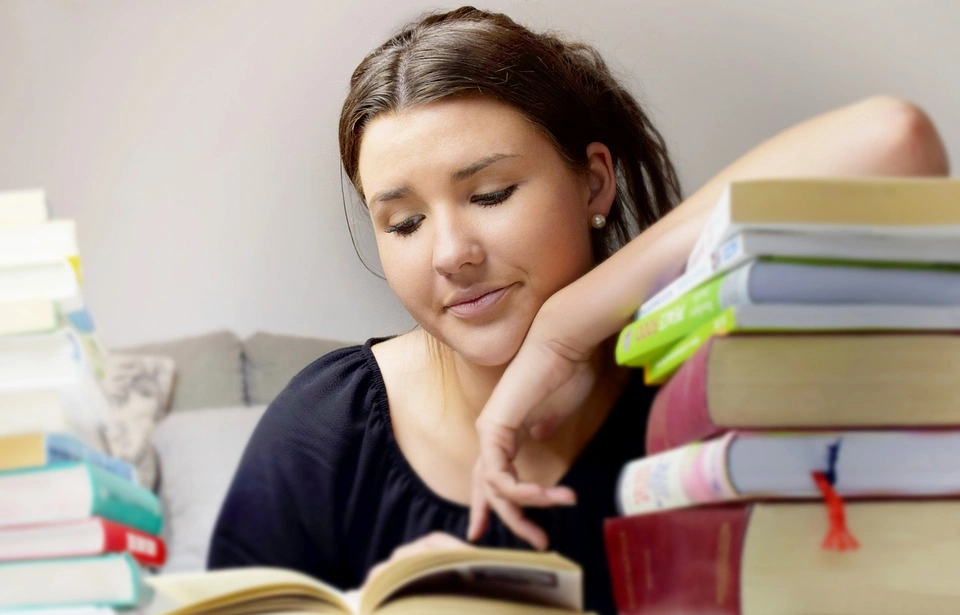 Mujer recargada sobre libros leyendo sobre un intercambio estudiantil en Acapulco.