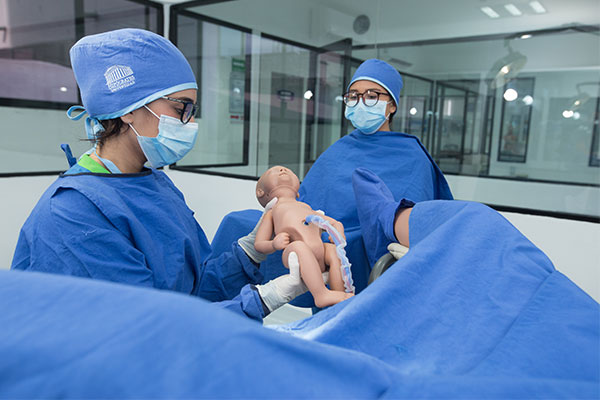 Estudiantes del área médico cirujano realizando práctica sobre labor de parto en laboratorio de Universidad Hipócrates.