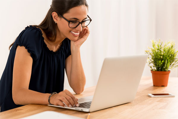 Mujer especializada en diplomado en planeación didacta argumentada trabajando sonrientemente en su computadora.