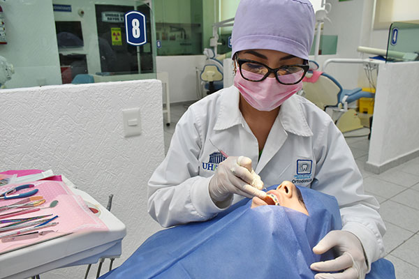 Alumna de la especialidad de ortodoncia realizando practicas con ayuda de otra persona con uso de herramientas en laboratorios de Universidad Hipócrates.