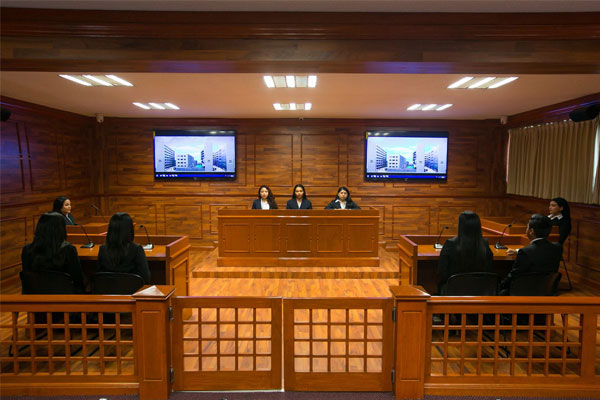 Estudiantes de licenciatura en derecho realizando práctica en tribunal con ayuda de profesores capacitados de Universidad Hipócrates.