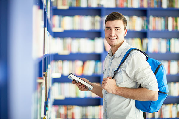Hombre joven sonriendo sosteniendo un libro