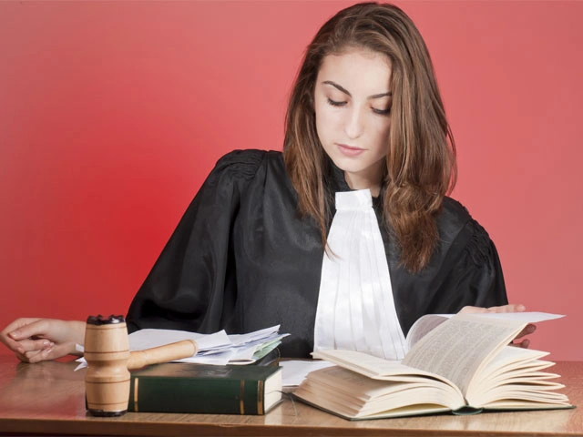 Mujer con vestimenta de juez leyendo libro.