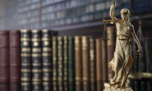 Libros de derecho detrás de estatua de justicia.