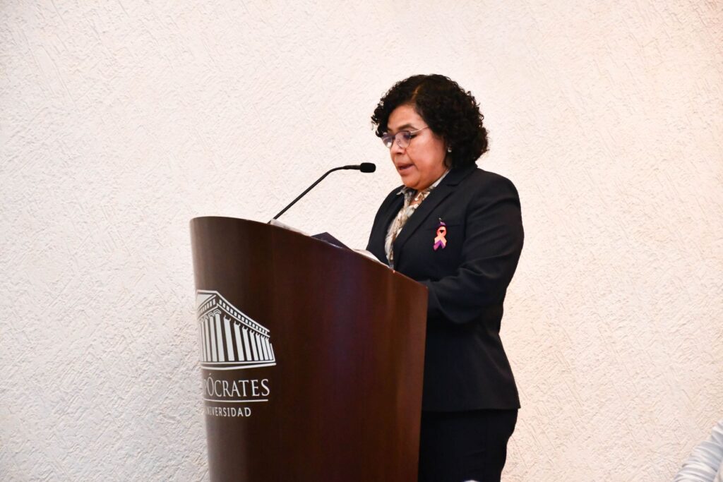 Persona dando un discurso desde el podio del Foro para celebrar el Día de la Mujer en la Universidad Hipócrates.