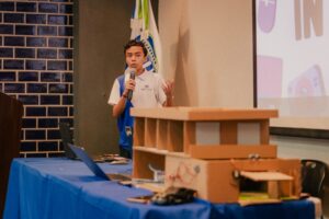 Alumno explicando su proyecto del prototipo de la casa inteligente.